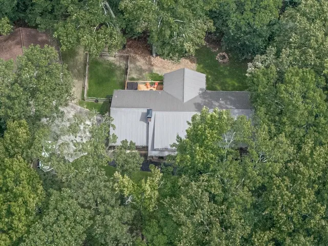 an aerial view of a house with a yard and trees all around