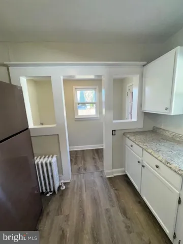 a view of an empty room with window and wooden floor