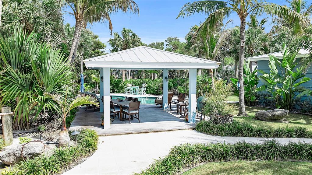 621 Casey Key Road Nokomis, FL 34275 - Photo 47 of 51 a view of a patio with table and chairs potted plants and palm trees