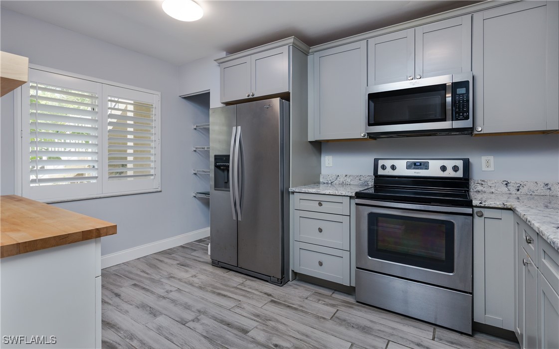 3451 County Barn Road, Unit G103 Naples, FL 34112 - Photo 8 of 25 a kitchen with stainless steel appliances a stove a microwave and a hard wood floors