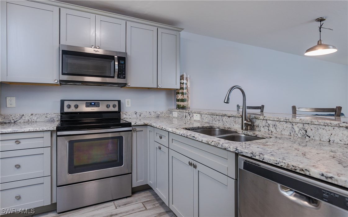 3451 County Barn Road, Unit G103 Naples, FL 34112 - Photo 9 of 25 a kitchen with granite countertop white cabinets and stainless steel appliances