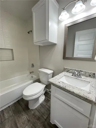 a bathroom with a granite countertop toilet sink and mirror