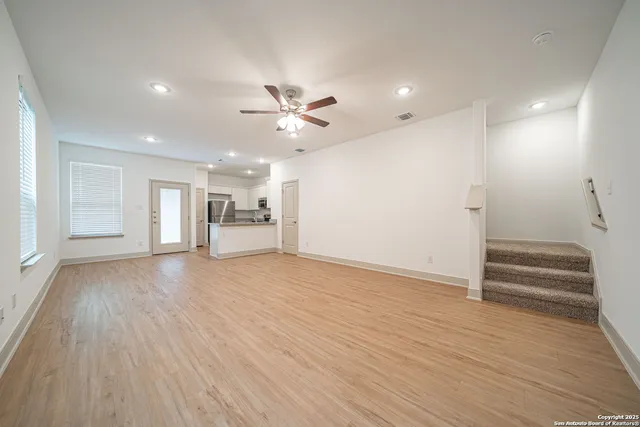 a view of an empty room with wooden floor and a window