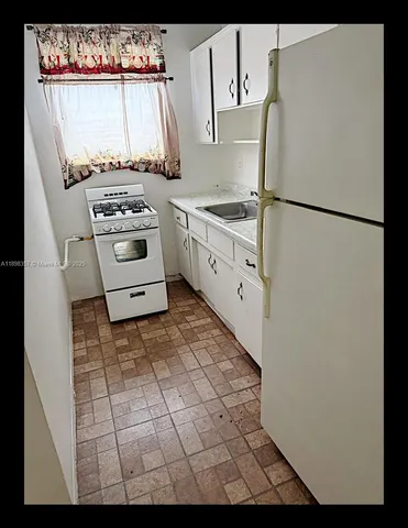 a kitchen with a stove a white cabinet and a refrigerator