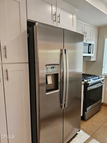 a metallic refrigerator freezer a stove top oven sitting inside of a kitchen