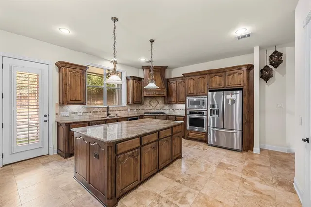 a kitchen with stainless steel appliances kitchen island granite countertop a refrigerator and stove top oven
