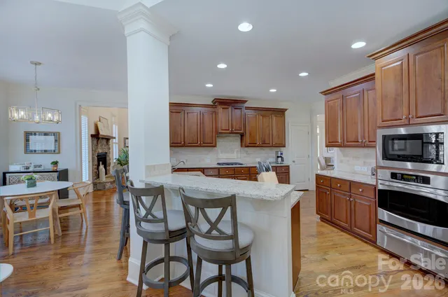 a kitchen with granite countertop kitchen island stainless steel appliances a stove a sink a refrigerator cabinets and dining table