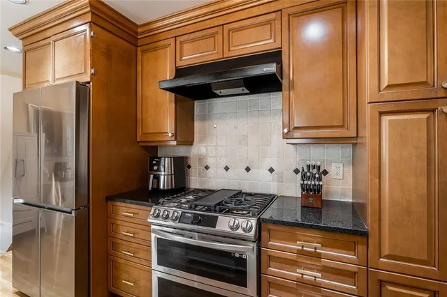 a kitchen with stainless steel appliances granite countertop a stove and a refrigerator with cabinets