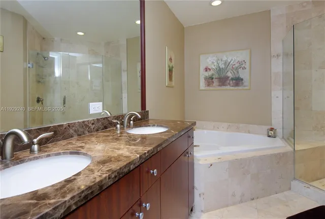 a bathroom with a granite countertop sink a mirror a bathtub and shower
