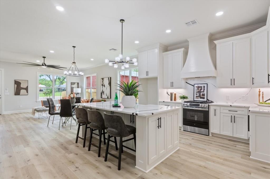 a kitchen with stainless steel appliances kitchen island granite countertop a table chairs sink and cabinets