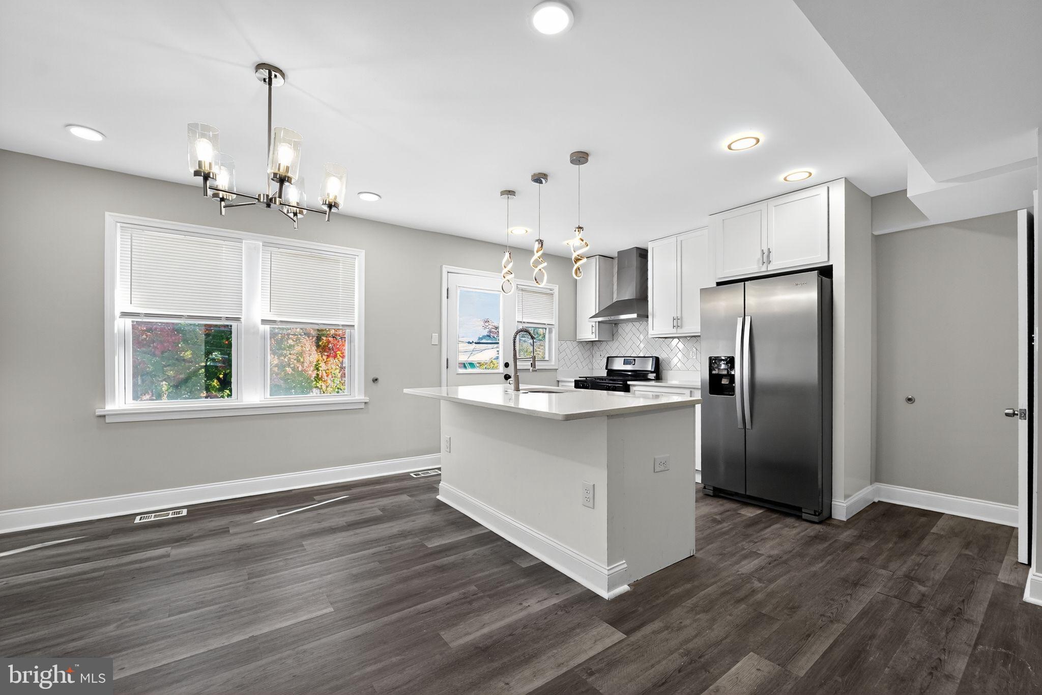 3807 Elkader Road Baltimore, MD 21218 - Photo 6 of 30 a kitchen with stainless steel appliances granite countertop a refrigerator a sink dishwasher a stove and white countertops with wooden floor