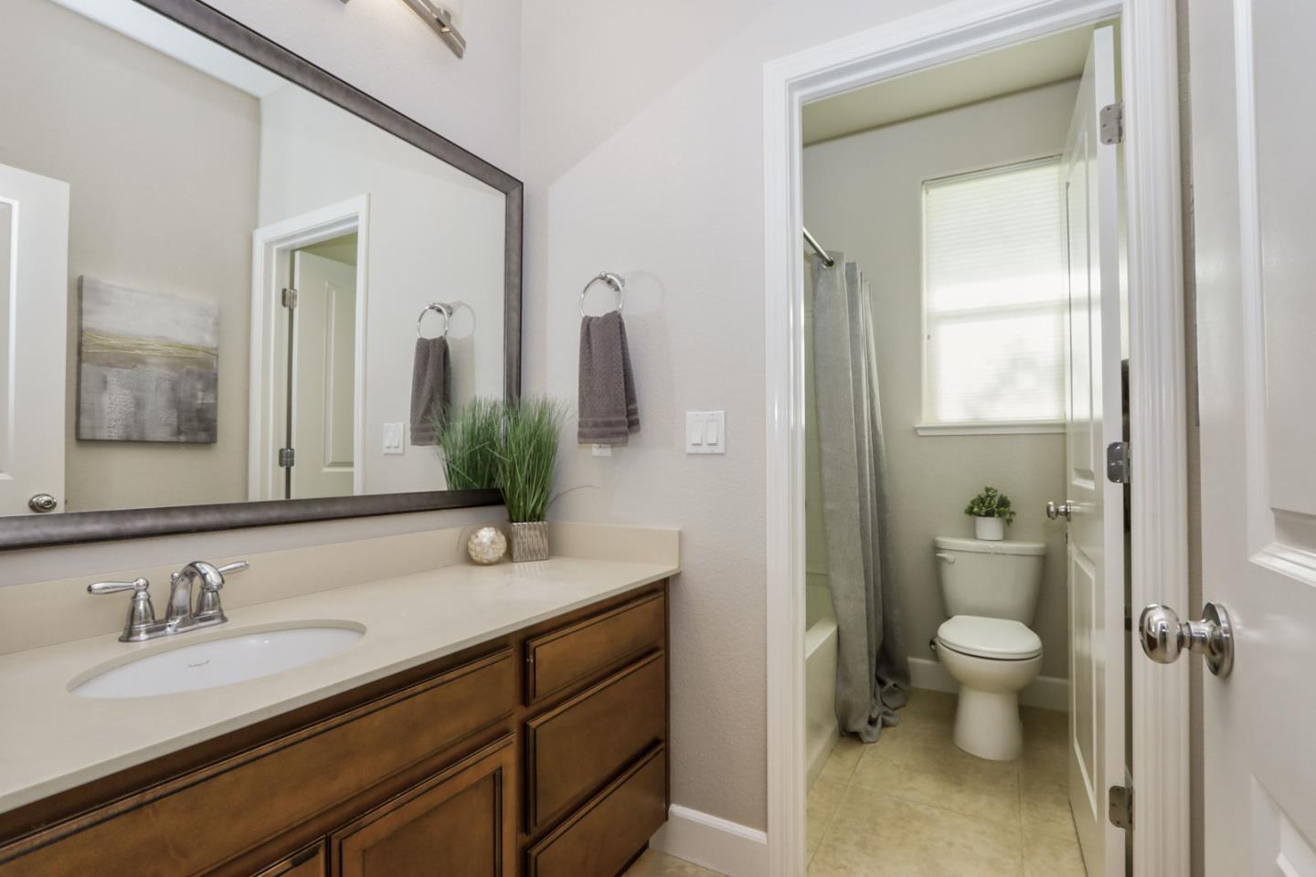 9534 Rodeo Drive Gilroy, CA 95020 - Photo 38 of 73 a bathroom with a granite countertop sink a toilet and a mirror