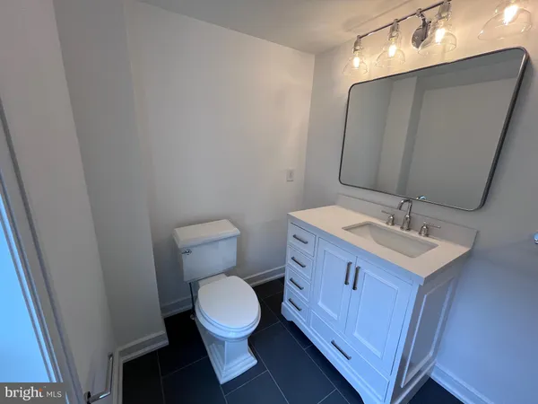 a bathroom with a toilet a sink a mirror and vanity