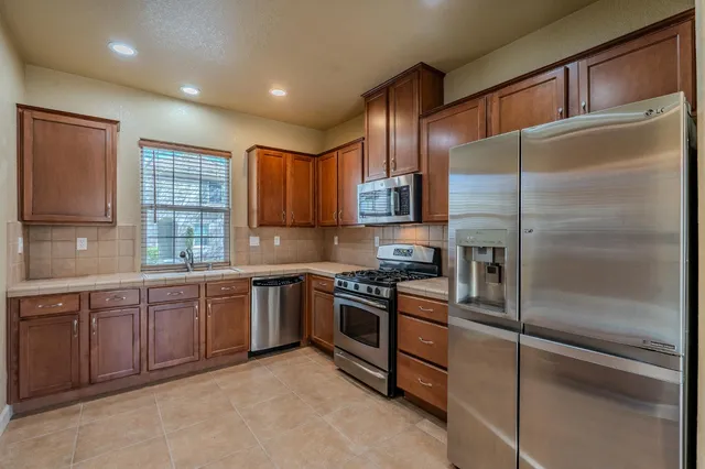 a kitchen with kitchen island granite countertop wooden cabinets stainless steel appliances and a sink