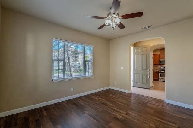 a view of an empty room with a window and wooden floor