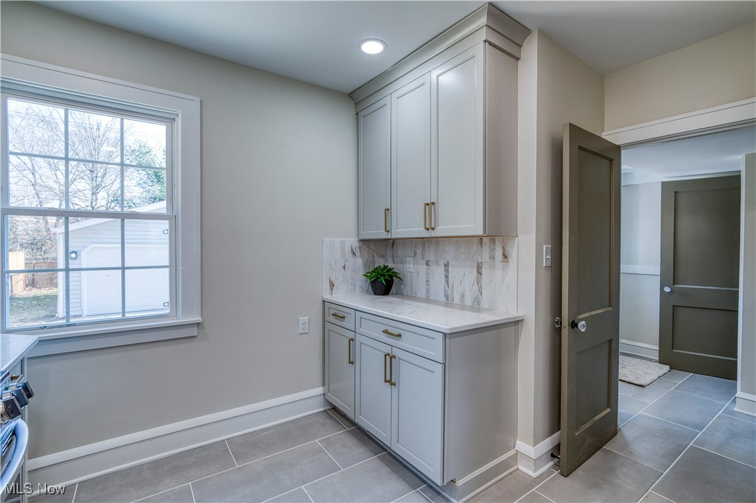 3081 Huntington Road Cleveland, OH 44120 - Photo 11 of 44 Kitchen featuring decorative backsplash, light tile patterned flooring, light stone countertops, and baseboards