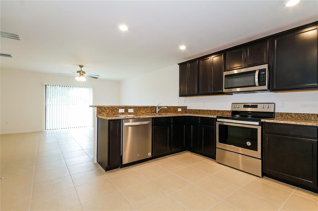 8615 Silverbell Loop Brooksville, FL 34613 - Photo 6 of 16 a kitchen with stainless steel appliances kitchen island granite countertop a stove and a microwave