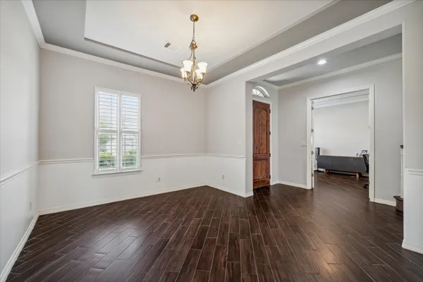 an empty room with wooden floor chandelier and windows