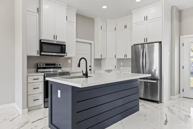 a kitchen with stainless steel appliances granite countertop a refrigerator stove a sink and white cabinets