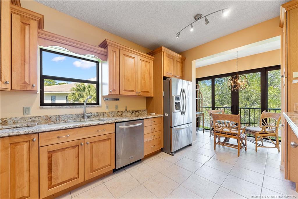 a open kitchen with stainless steel appliances granite countertop a stove top oven a refrigerator a dining table and chairs with the outer view