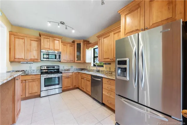 a kitchen with stainless steel appliances granite countertop a refrigerator a stove a sink and dishwasher