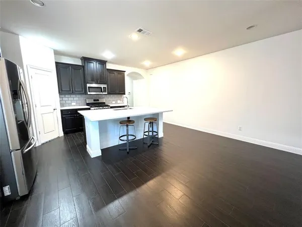 a kitchen with stainless steel appliances wooden floor and chairs