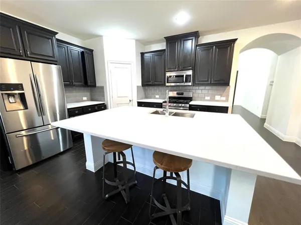 a kitchen with kitchen island a sink refrigerator and microwave