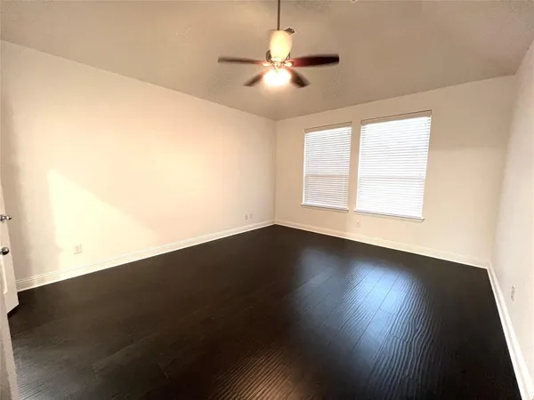 an empty room with wooden floor and fan