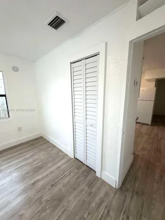 an empty room with wooden floor cabinet and windows