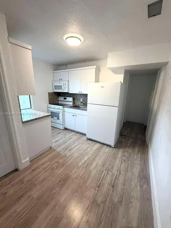 a kitchen with a refrigerator a stove top oven a sink and dishwasher with wooden floor