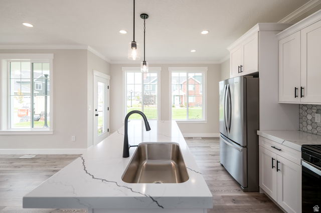 8797 Green Way, Unit 3 Sandy, UT 84094 - Photo 4 of 12 Kitchen featuring freestanding refrigerator, crown molding, pendant lighting, light stone counters, and white cabinets