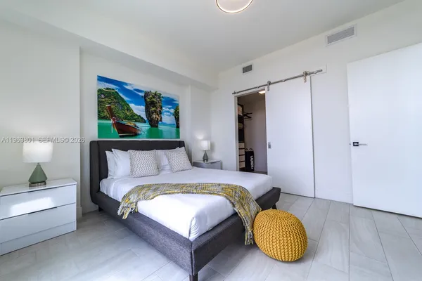 a bedroom with a bed cupboard mirror and window