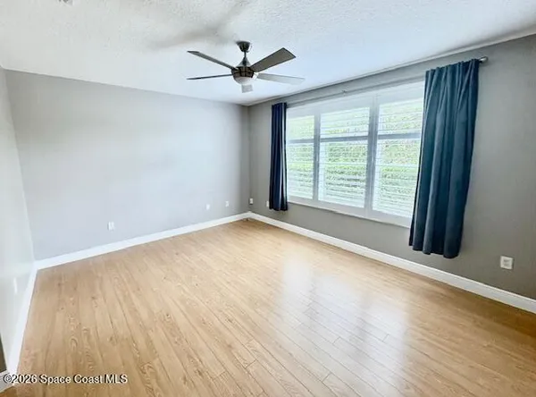 a view of an empty room with a window and wooden floor