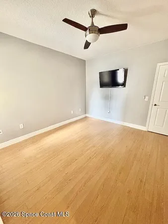 a view of a big room with wooden floor a ceiling fan and window