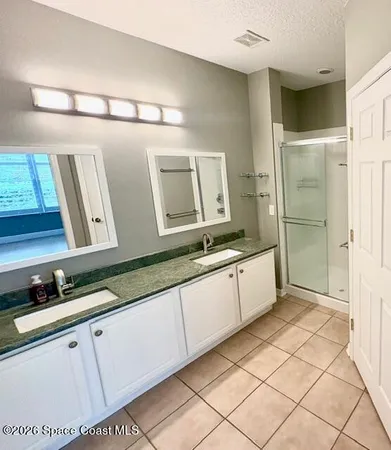 a spacious bathroom with a double vanity sink a mirror and a shower