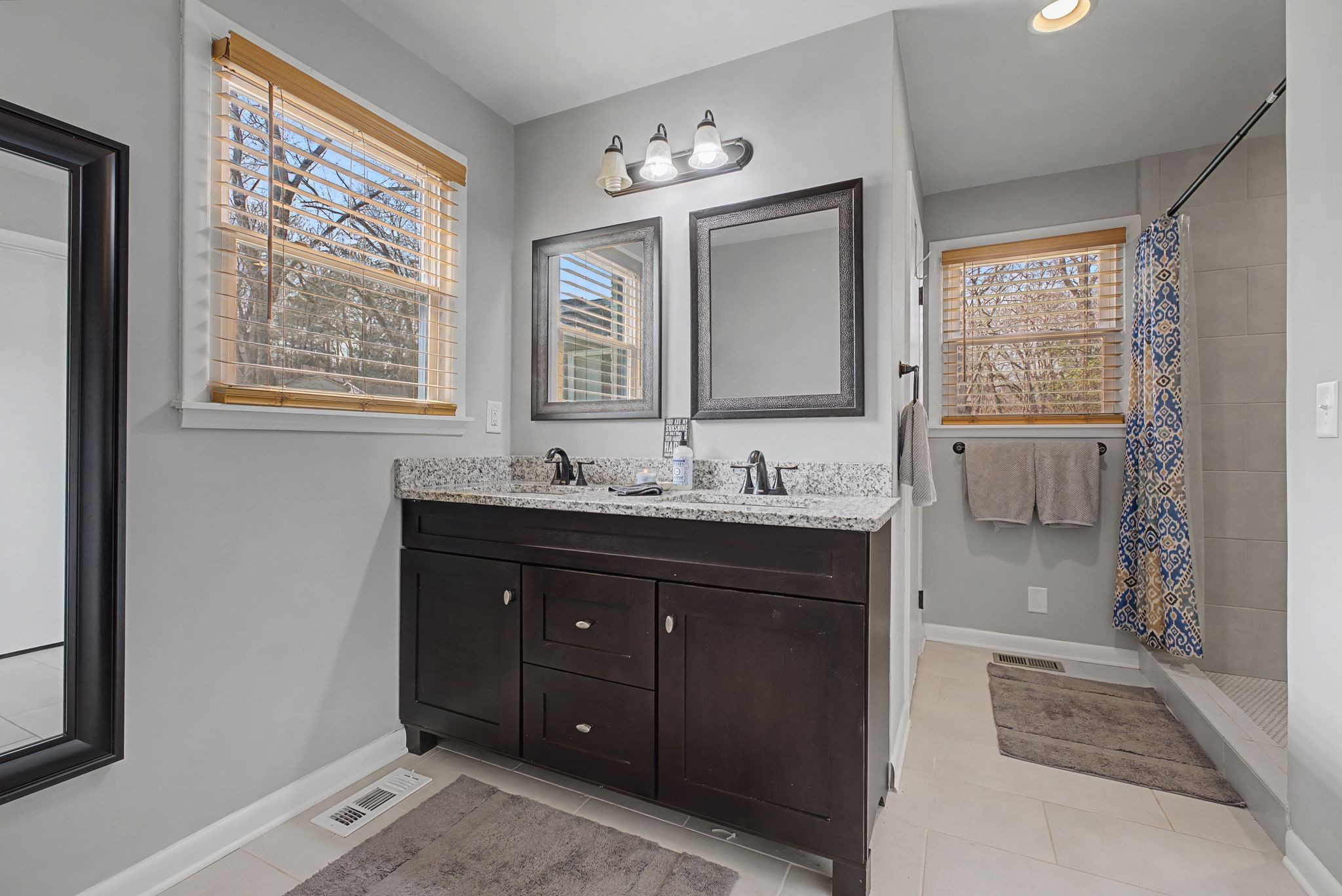 820 Allen Road Nashville, TN 37214 - Photo 15 of 28 a bathroom with a double vanity sink a mirror and a bathtub next to a window