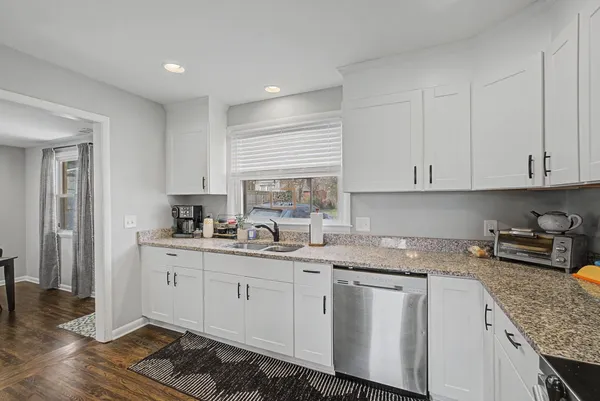 a kitchen with white cabinets sink and stove