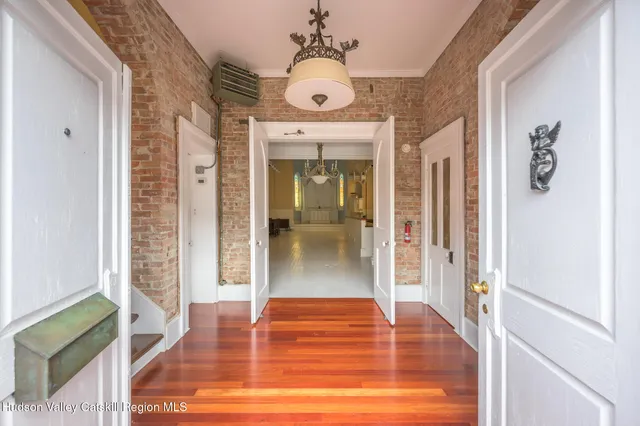 a view of a hallway with wooden floor and a living room