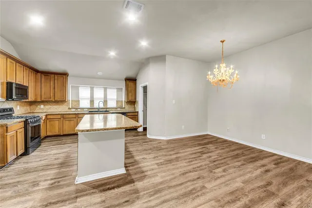 a view of kitchen with granite countertop cabinets and refrigerator