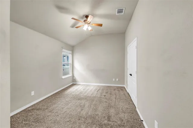 an empty room with windows and chandelier fan