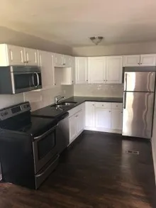 a kitchen with granite countertop a refrigerator stove top oven and sink