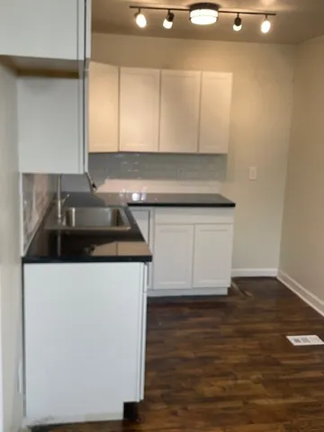 a kitchen with granite countertop a sink and a stove with wooden floor