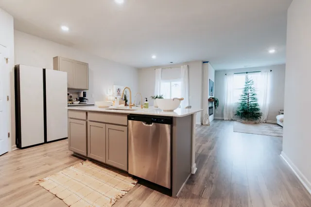 a kitchen with stainless steel appliances a sink a stove a refrigerator cabinets and wooden floor