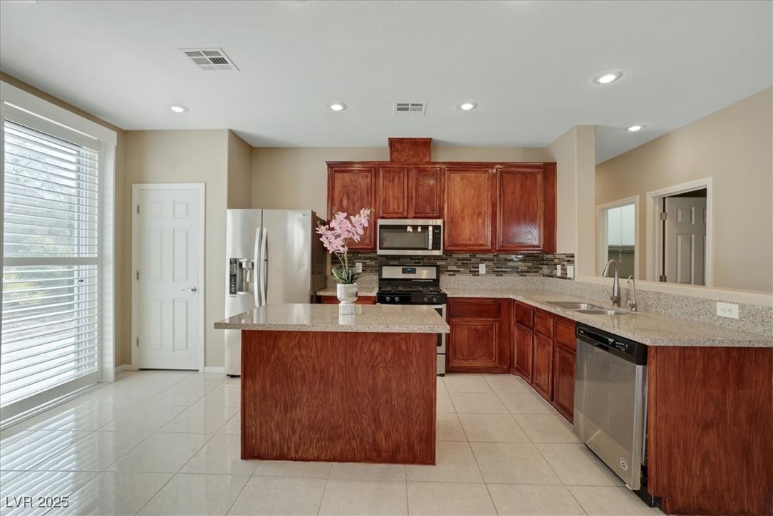 319 Fox Lake Avenue Las Vegas, NV 89148 - Photo 21 of 39 Kitchen featuring stainless steel appliances, tasteful backsplash, light tile patterned floors, a center island, and recessed lighting