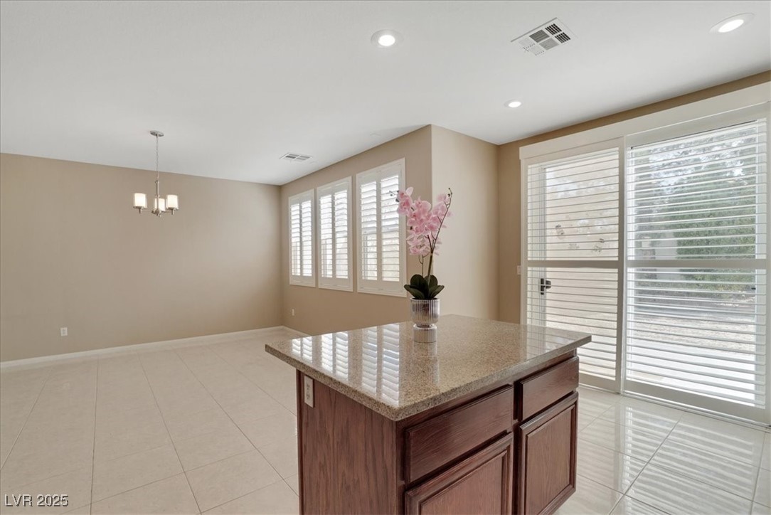 319 Fox Lake Avenue Las Vegas, NV 89148 - Photo 23 of 39 Kitchen featuring hanging light fixtures, a kitchen island, recessed lighting, light stone countertops, and light tile patterned floors
