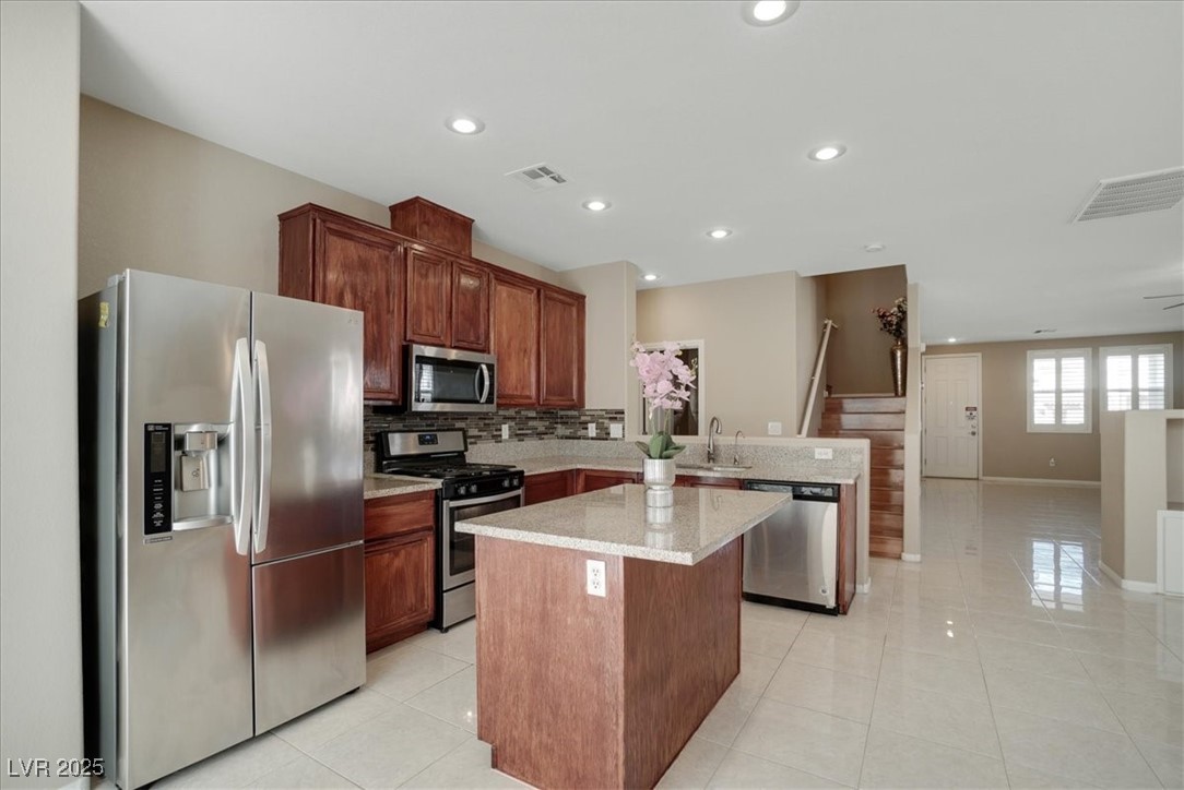 319 Fox Lake Avenue Las Vegas, NV 89148 - Photo 39 of 39 Kitchen with appliances with stainless steel finishes, light tile patterned floors, tasteful backsplash, a center island, and open floor plan