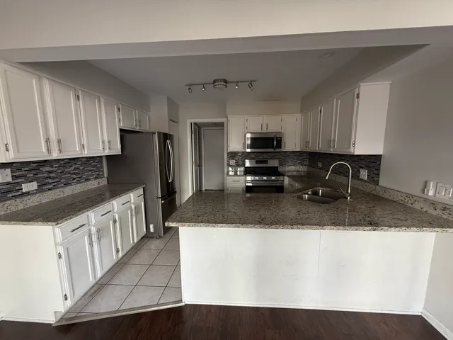 a kitchen with stainless steel appliances granite countertop a sink a stove a refrigerator a microwave and cabinets