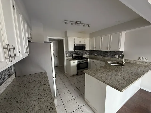 a kitchen with stainless steel appliances granite countertop a sink a stove a refrigerator a microwave and cabinets