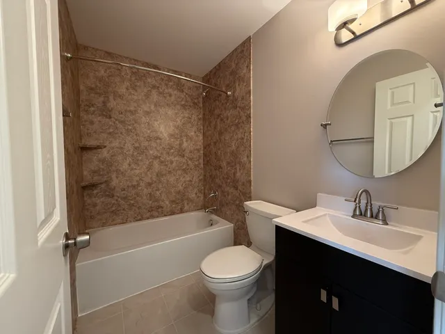 a bathroom with a bathtub shower sink vanity mirror and toilet