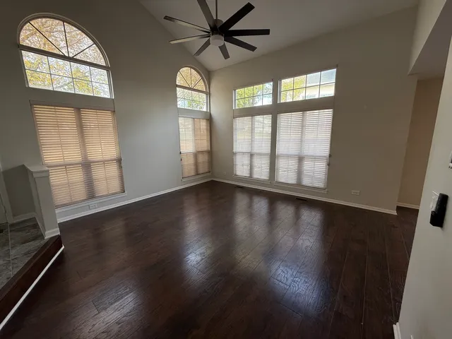 an empty room with wooden floor fan and windows